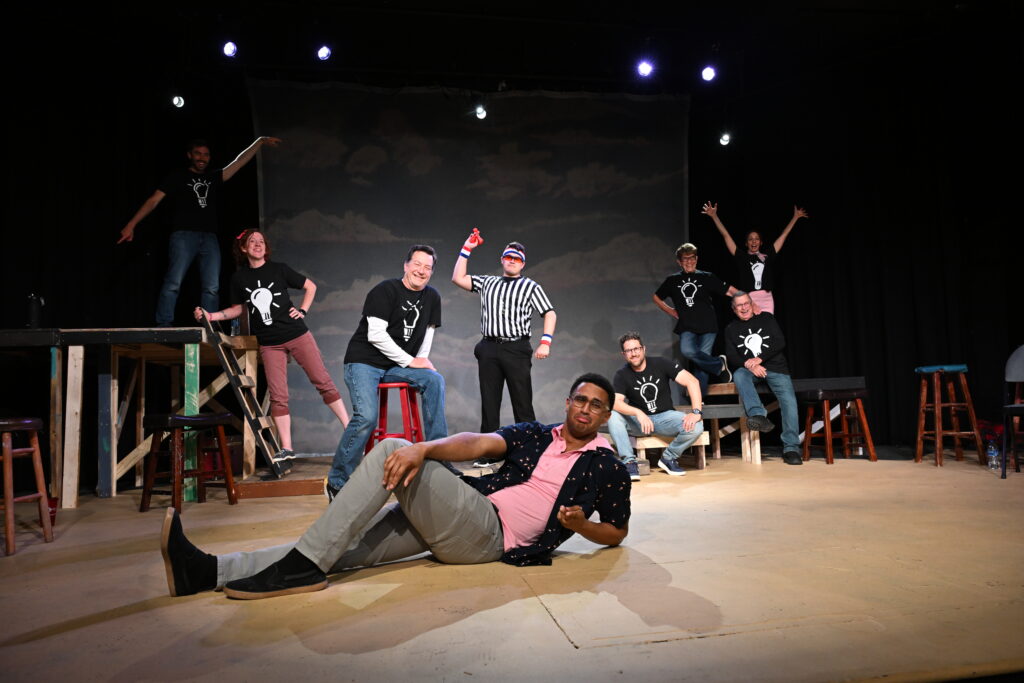The WIT! troupe posed across the Woodstock Arts stage in their lightbulb shirts