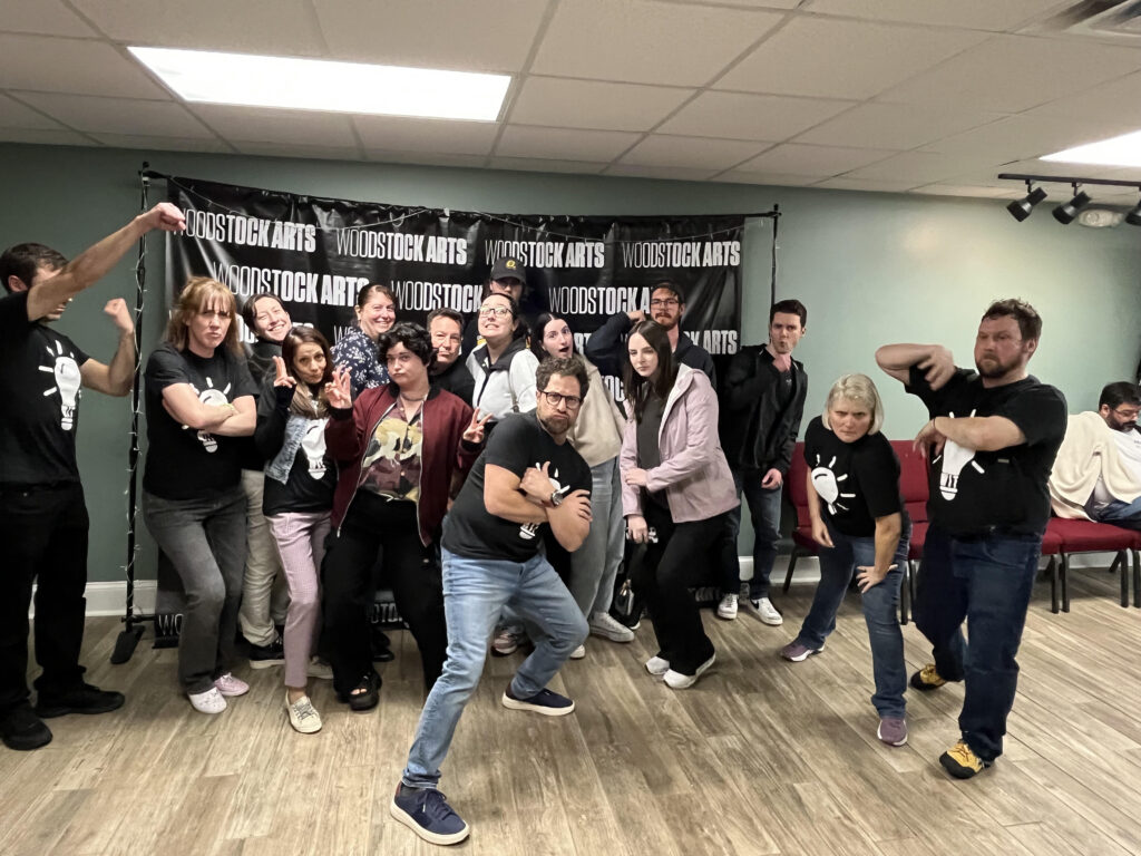 An improv class group in front of the Woodstock Arts step and repeat